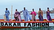 Modelki i modele prezentują kreacje na tradycyjnej łodzi rybackiej podczas Dakar Fashion Week w Dakarze, Senegal, 6 grudnia 2025 r.