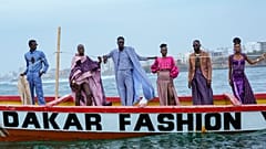 Mankenler, Dakar, Senegal'de 6 Aralık 2025'te Dakar Moda Haftası sırasında geleneksel bir balıkçı teknesinde tasarımlarını sergiliyor.
