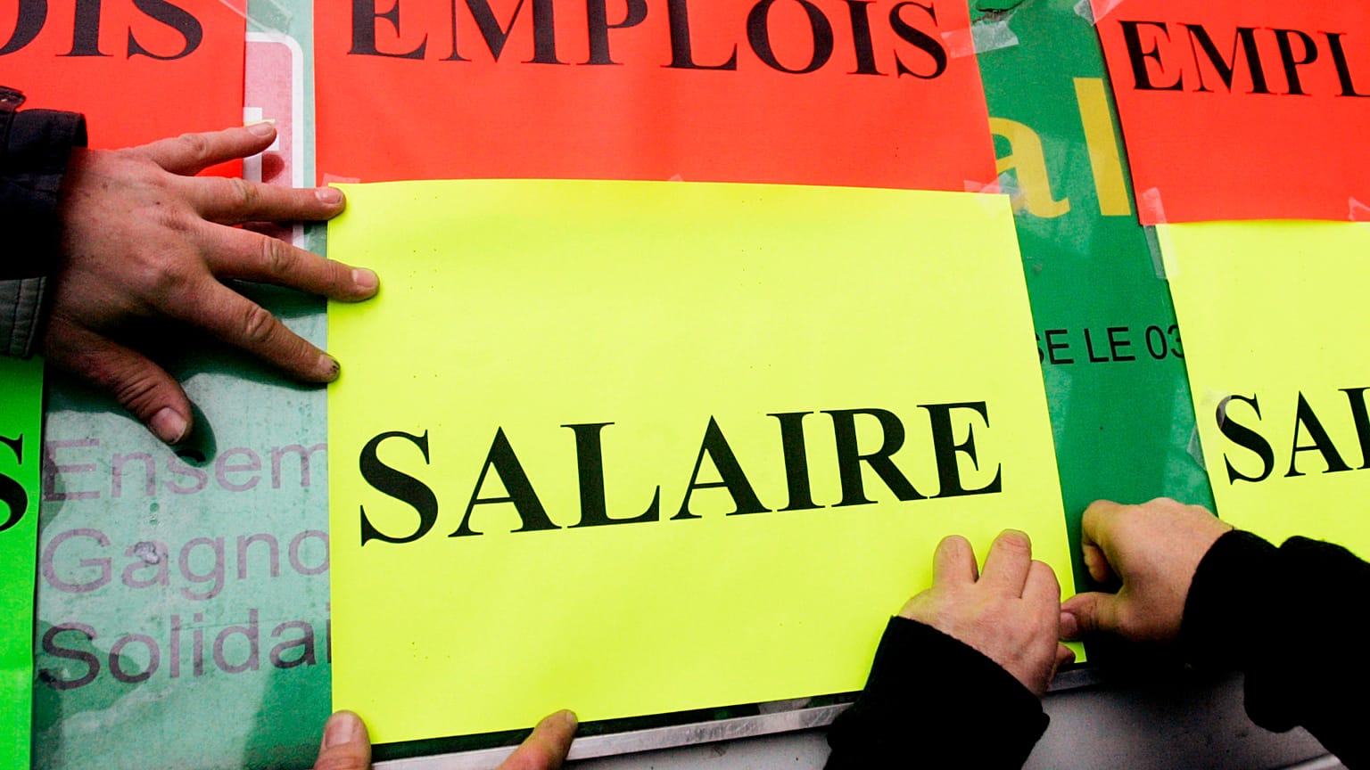 Dipendenti pubblici affiggono cartelli con le scritte "Jobs", in alto, e "Salary" durante una protesta per gli stipendi a Lille, nel nord della Francia. 2 febbraio 2006.