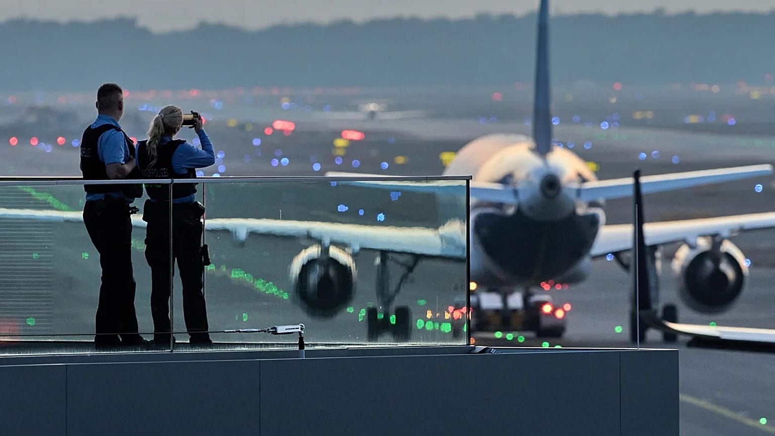 Polizeibeamte beobachten, wie Flugzeuge ihre Parkpositionen auf dem Frankfurter Flughafen einnehmen.