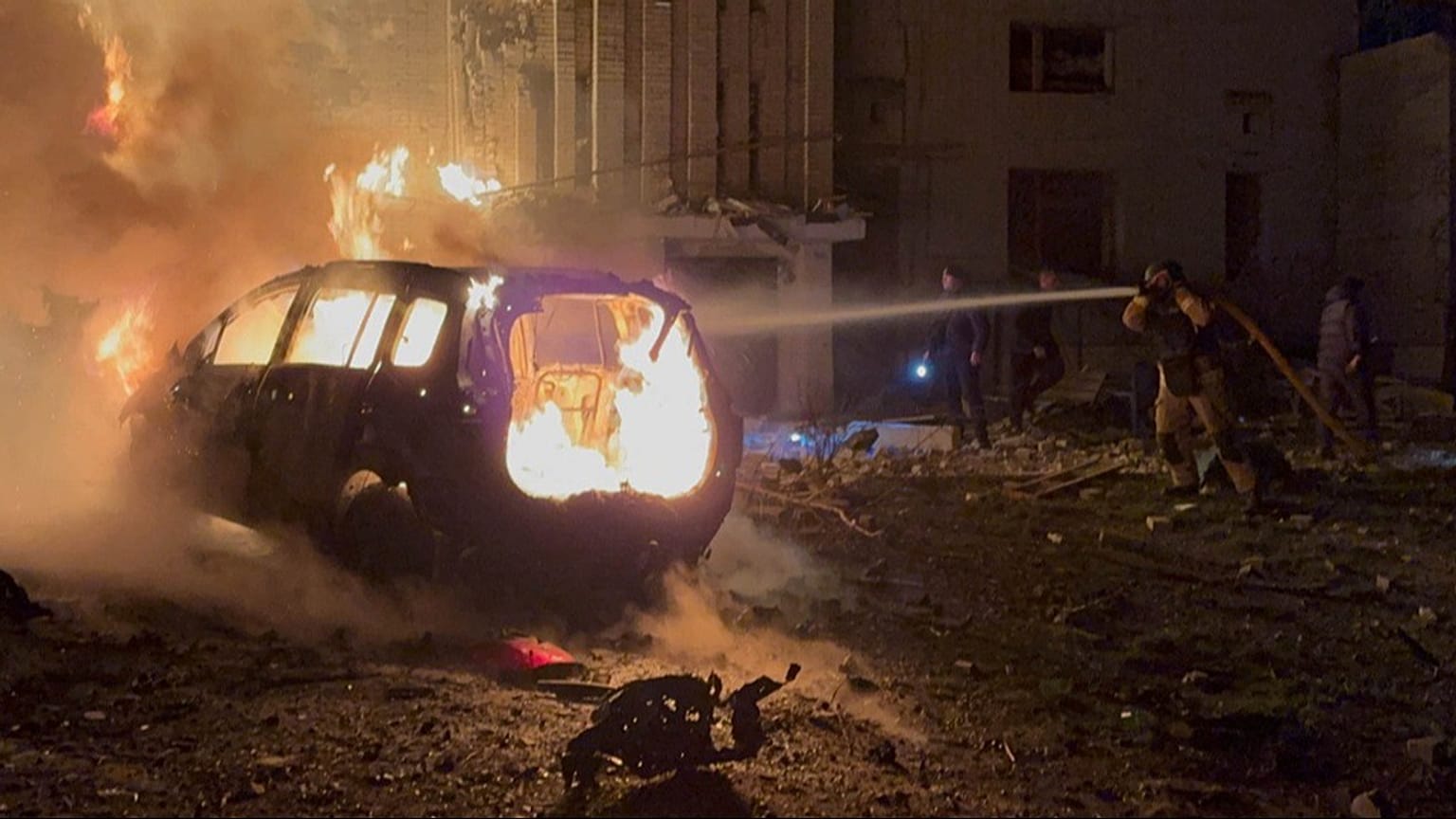 A rescue worker puts out a fire of a car in front of a residential building damaged by a Russian strike in Sumy region, Ukraine, Monday, Dec. 8, 2025