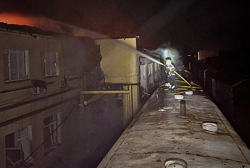 A rescue worker puts out a fire of a car in front of a residential building damaged by a Russian strike in Sumy region, Ukraine, Monday, Dec. 8, 2025