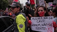 Kadın cinayetlerine karşı bir yürüyüşte, bir gösterici üzerinde Portekizce 'Kadın, susma! Erkek, kendini muaf tutma' yazan bir pankartı havaya kaldırıyor.