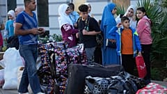 عائلة لاجئة سورية تقف بجانب متعلقاتها عند نقطة تجمع, بينما ينتظرون أن تفحصهم قوات الأمن اللبنانية قبل ركوب الحافلات للعودة إلى ديارهم في سوريا, في بيروت, لبنان,, سبتمبر 2025