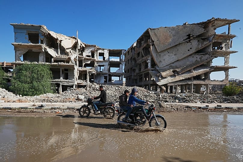 دراجات نارية تعبر بمحاذاة مبنى متضرر من الحرب في حيّ اليرموك بدمشق، في 20 ديسمبر 2025.