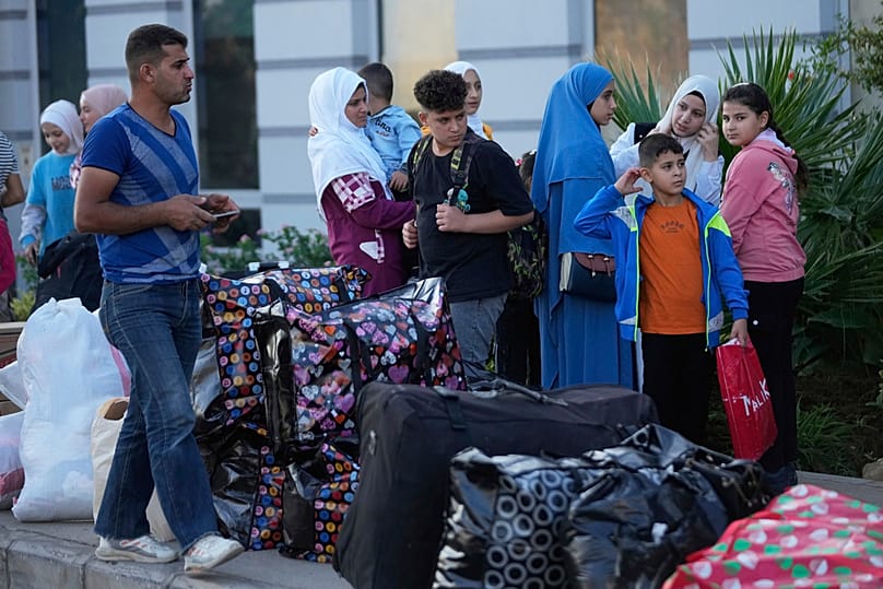 عائلة سورية نازحة تقف قرب أمتعتها في نقطة تجمّع بانتظار التفتيش من قبل القوى الأمنية اللبنانية قبل انطلاق الحافلات للعودة إلى سوريا من بيروت، في 20 سبتمبر 2025.