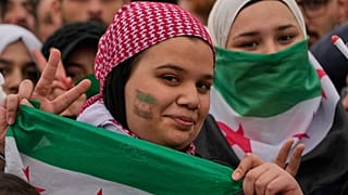 فتيات يرفعن لافتات النصر أثناء تجمعهن للاحتفالات بالذكرى الأولى للإطاحة بالرئيس السابق بشار الأسد في دمشق، سوريا، الاثنين 8 ديسمبر 2025. 