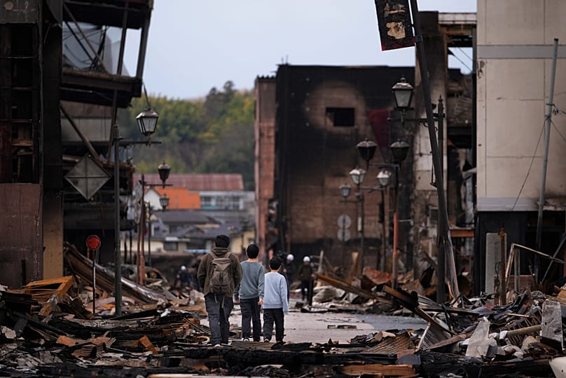 People walk through debris of buildings on the Asaichi-dori shopping street in Wajima in the Noto peninsula, 5 January, 2024