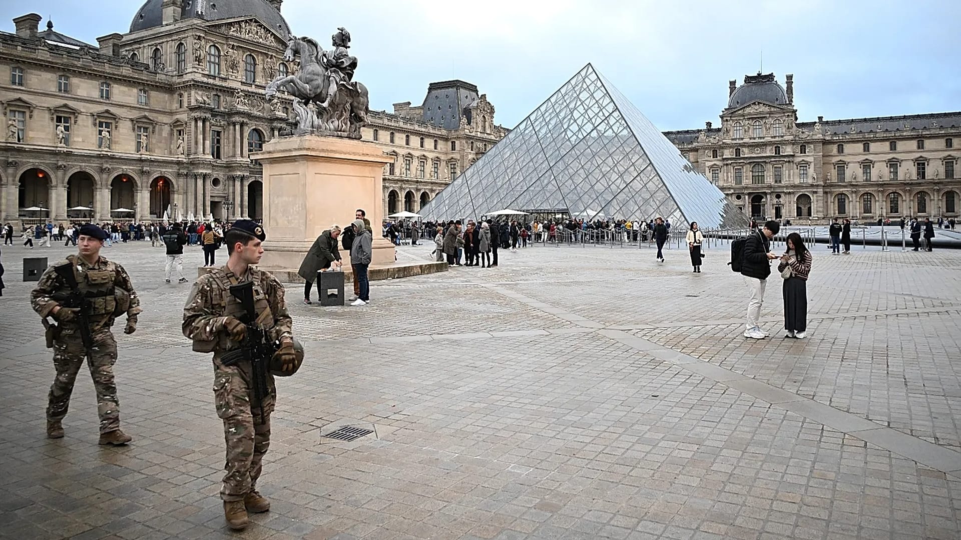 Des soldats patrouillent alors que des personnes font la queue pour entrer au musée du Louvre à Paris, le 20 octobre 2025. 