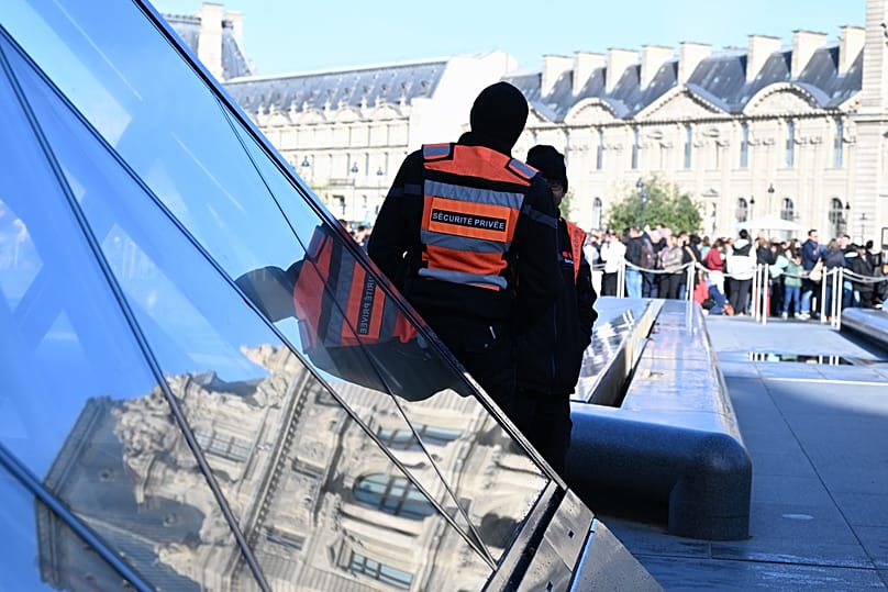 Private security members watch people queueing outside the Louvre museum in Paris, 30 October, 2025 