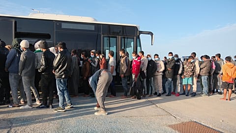 Migranten steigen am Sonntag, dem 19. Oktober 2025, im Hafen von Paliochora auf der Insel Kreta in einen Bus.