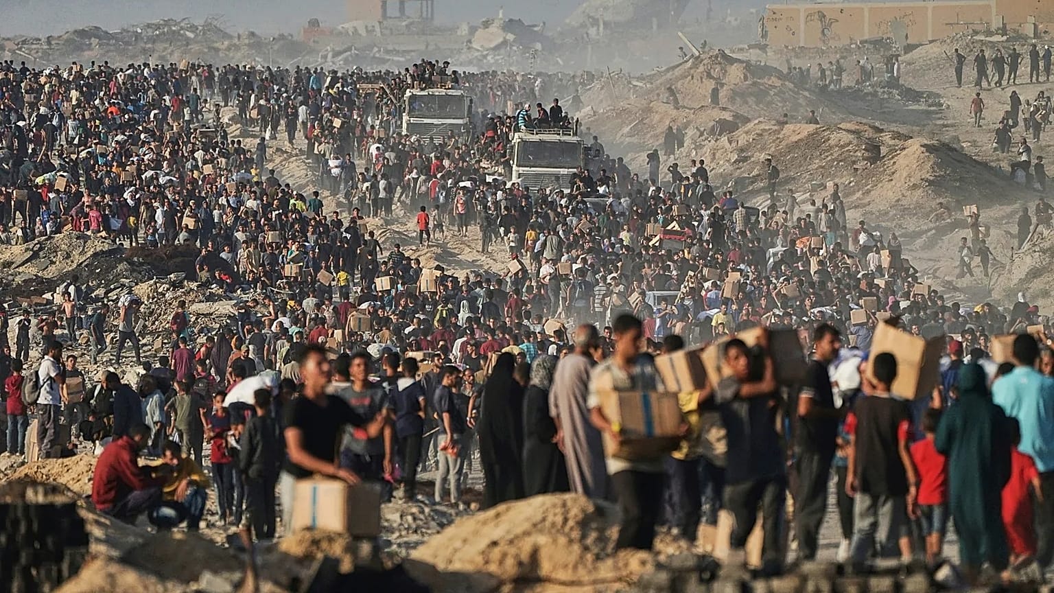 People carry sacks and boxes of food and humanitarian aid that was unloaded from a World Food Programme convoy that had been heading to Gaza City, 16 June, 2025