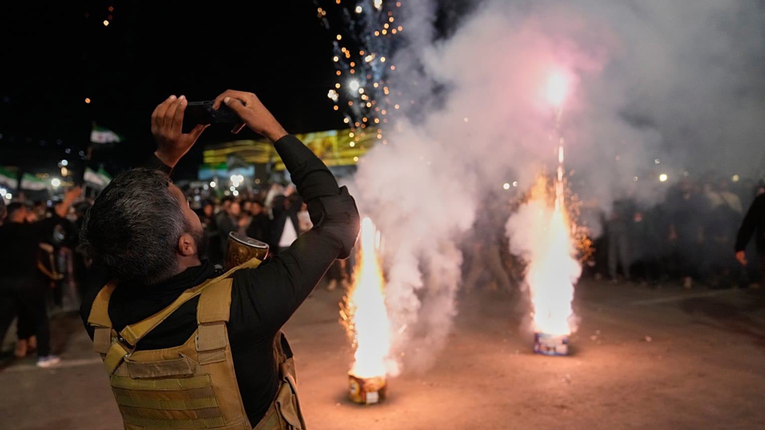 شرطي سوري يلتقط صوراً للألعاب النارية خلال الاحتفالات بالذكرى الأولى للإطاحة بالرئيس السابق بشار الأسد في دمشق، سوريا، الاثنين 8 ديسمبر 2025.  