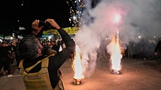 شرطي سوري يلتقط صوراً للألعاب النارية خلال الاحتفالات بالذكرى الأولى للإطاحة بالرئيس السابق بشار الأسد في دمشق، سوريا، الاثنين 8 ديسمبر 2025.  