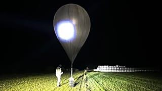 FILE: In this undated photo released by Lithuania's State Border Guard Service, an officer inspects a balloon used to carry cigarettes into Lithuania