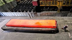 Duisburg, Almanya'daki thyssenkrupp çelik fabrikasında bir adam kızgın çelik plakanın yanından geçiyor. 5 Kasım 2025.