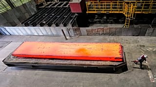 A man walkes past a glowing steel plate at the thyssenkrupp steel mill in Duisburg, Germany. 5 Nov. 2025.