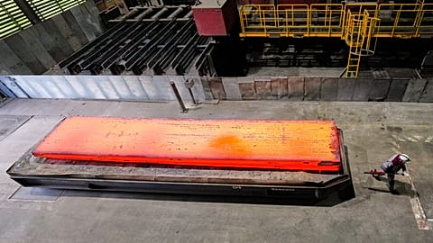 A man walkes past a glowing steel plate at the thyssenkrupp steel mill in Duisburg, Germany. 5 Nov. 2025.