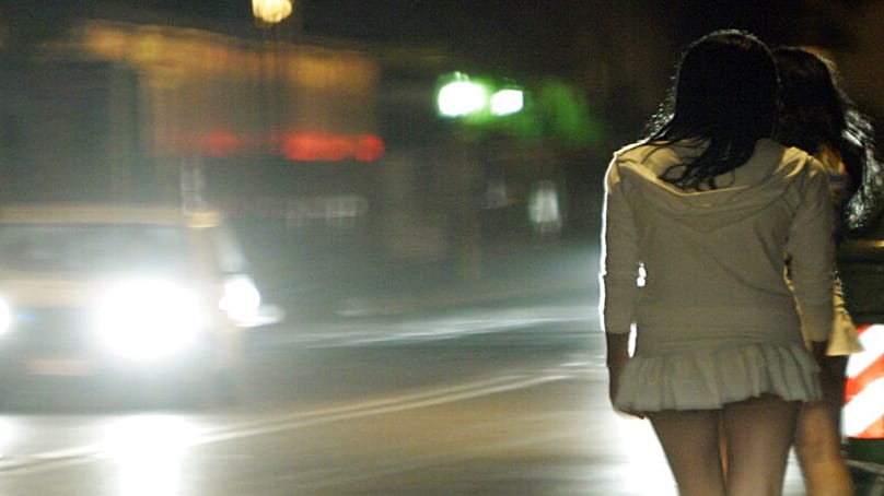 نساء يقفن ليلًا على الرصيف