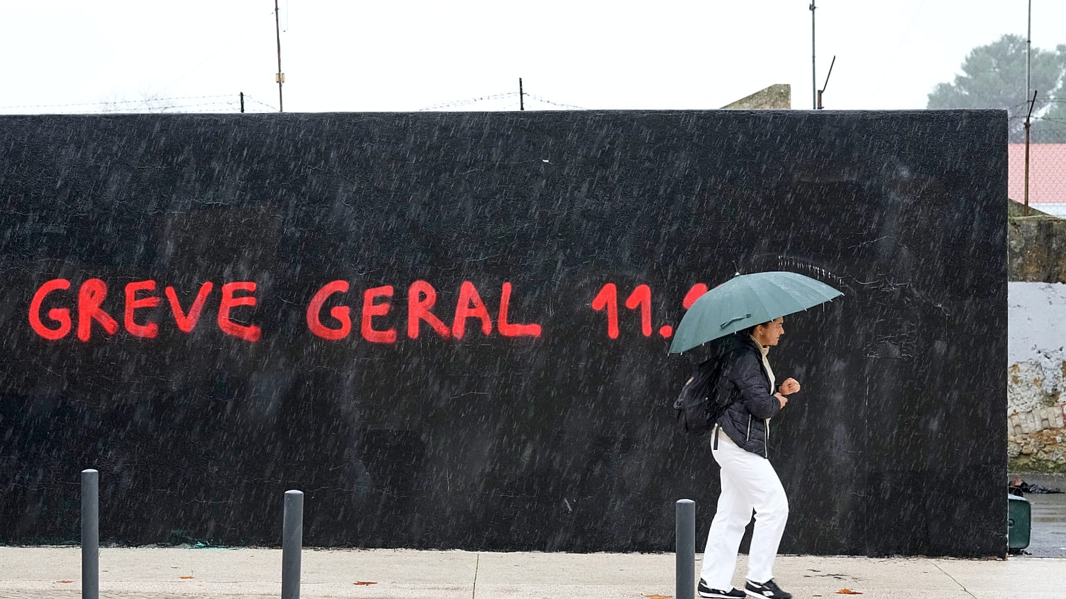  Article Image  portugal   BACK  IMPORT Portugal General Strike  A woman walks past a graffiti with the words "Greve Geral" (General Strike)