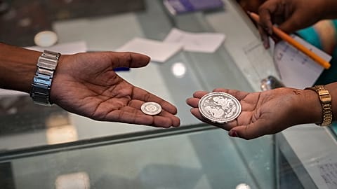 FILE - A saleswoman, right, shows a silver coin to a customer on Dhanteras, an auspicious day to purchase gold, silver and utensils. October 2025