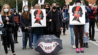 Aktywistki praw kobiet z plakatami akcji Strajku Kobiet protestują przeciwko niedawnemu zaostrzeniu restrykcyjnego prawa aborcyjnego w Polsce przed budynkiem parlamentu