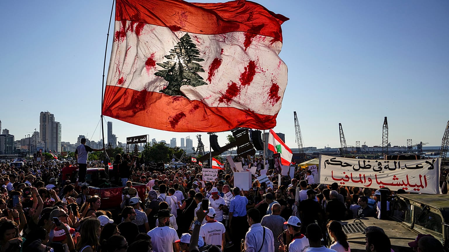 لبنانيون يرفعون علماً ضخماً خلال تجمع لإحياء الذكرى الثالثة للانفجار أمام مرفأ بيروت، في 4 آب 2023.