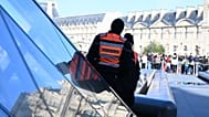 FILE: Private security members watch people queueing outside the Louvre museum, Paris, 30 October 2025