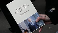 A man holds a book of former French President Nicolas Sarkozy "Diary of a Prisoner" in front a Paris bookshop, 10 December, 2025
