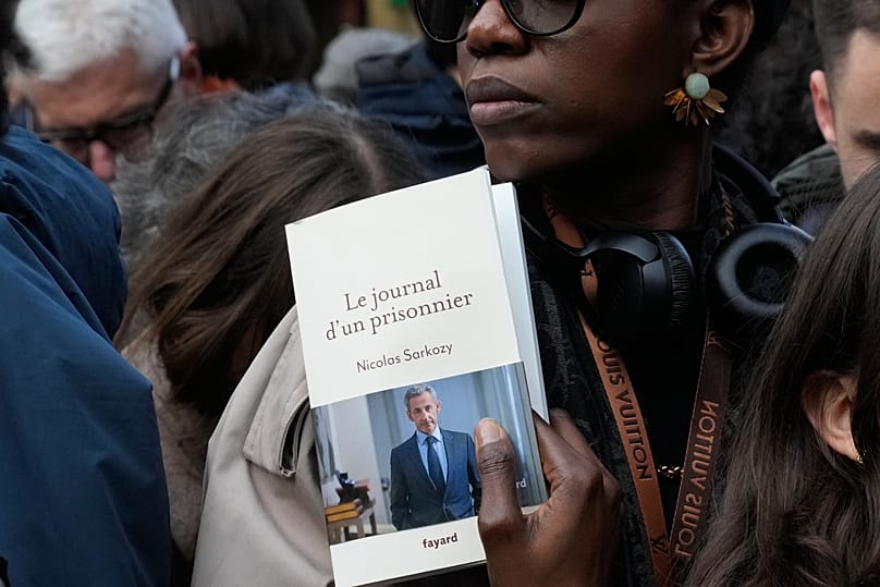 A woman holds a book of former French President Nicolas Sarkozy "Diary of a Prisoner" in Paris, 10 December, 2025
