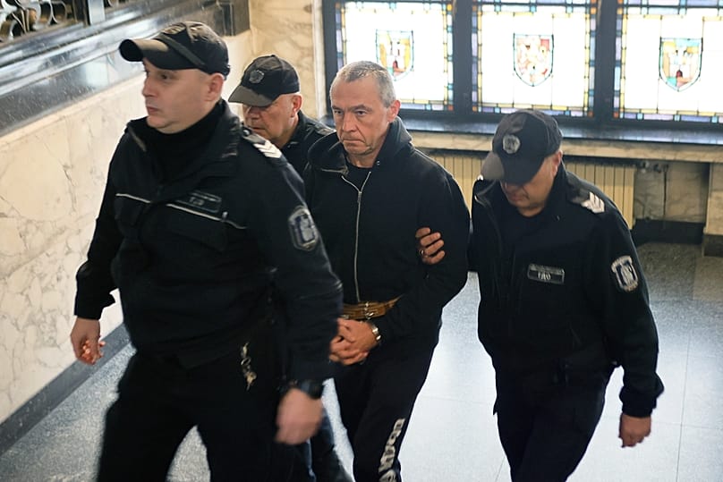 Police escort Igor Grechushkin from the court in Sofia, 10 December, 2025