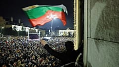Студент размахивает болгарским флагом, когда десятки тысяч болгар собрались на центральной площади Софии, требуя отставки правительства, София, 10 декабря 2025 г.