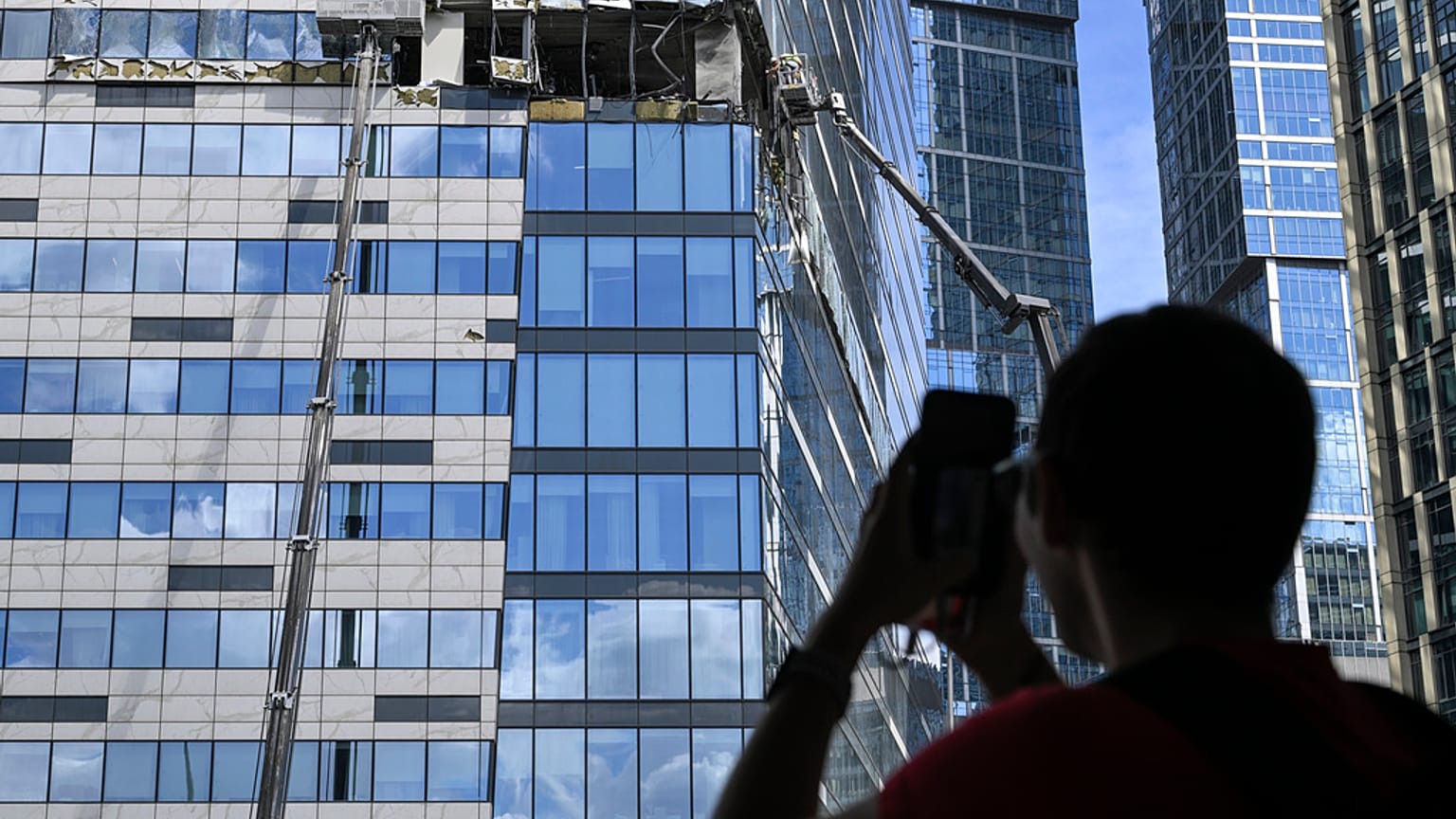 Мужчина фотографирует на мобильный телефон поврежденный небоскреб в районе "Москва-Сити" после сообщения об атаке БПЛА в Москве. 30 июля 2023 года. 