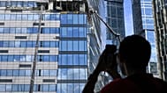 Мужчина фотографирует на мобильный телефон поврежденный небоскреб в районе "Москва-Сити" после сообщения об атаке БПЛА в Москве. 30 июля 2023 года. 