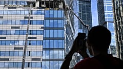 Мужчина фотографирует на мобильный телефон поврежденный небоскреб в районе "Москва-Сити" после сообщения об атаке БПЛА в Москве. 30 июля 2023 года. 