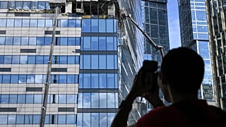 Мужчина фотографирует на мобильный телефон поврежденный небоскреб в районе "Москва-Сити" после сообщения об атаке БПЛА в Москве. 30 июля 2023 года. 