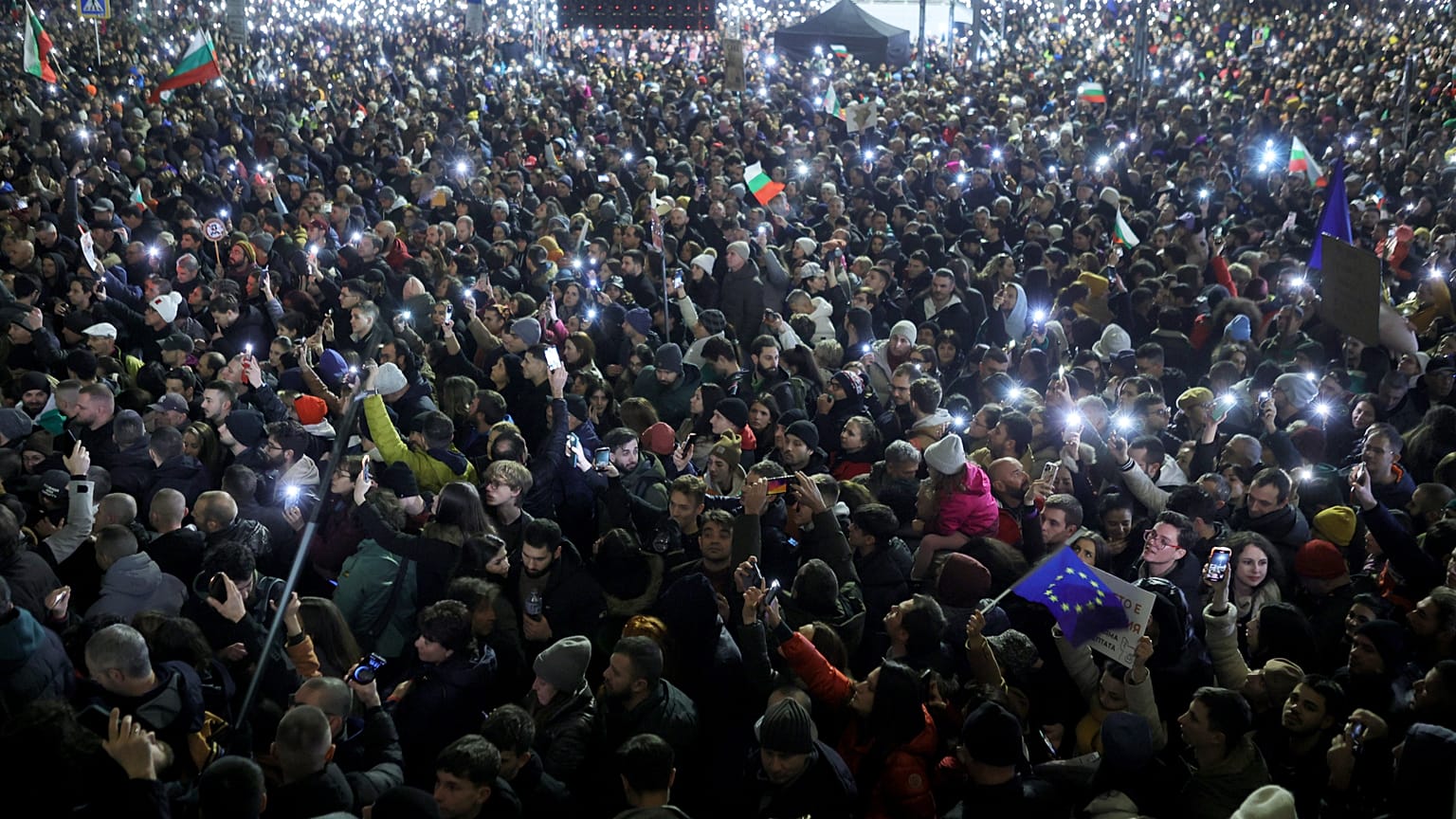 Des manifestants brandissent leurs téléphones allumés en guise de torches, tandis qu'une foule de dizaines de milliers de Bulgares remplit la place centrale de Sofia.