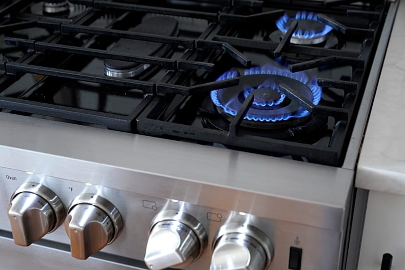 Flames emerge from burners on a natural gas stove. 