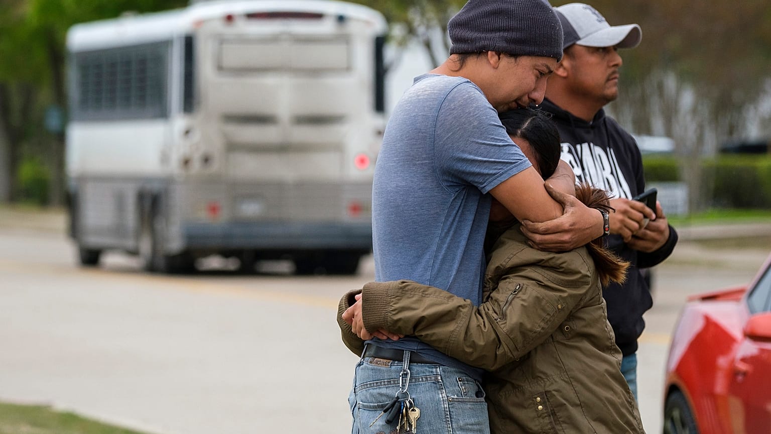 ARCHIVO - En esta foto del 3 de abril de 2019, una pareja se abraza afuera de CVE Group mientras un autobús de LaSalle Corrections Transport sale de las instalaciones en Allen