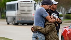 ARCHIVO - En esta foto del 3 de abril de 2019, una pareja se abraza afuera de CVE Group mientras un autobús de LaSalle Corrections Transport sale de las instalaciones en Allen