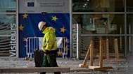 Un ouvrier du bâtiment se tient devant une porte ornée des étoiles de l'UE, au siège de l'UE à Bruxelles, le 9 octobre 2019