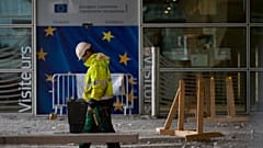 Un ouvrier du bâtiment se tient devant une porte ornée des étoiles de l'UE, au siège de l'UE à Bruxelles, le 9 octobre 2019