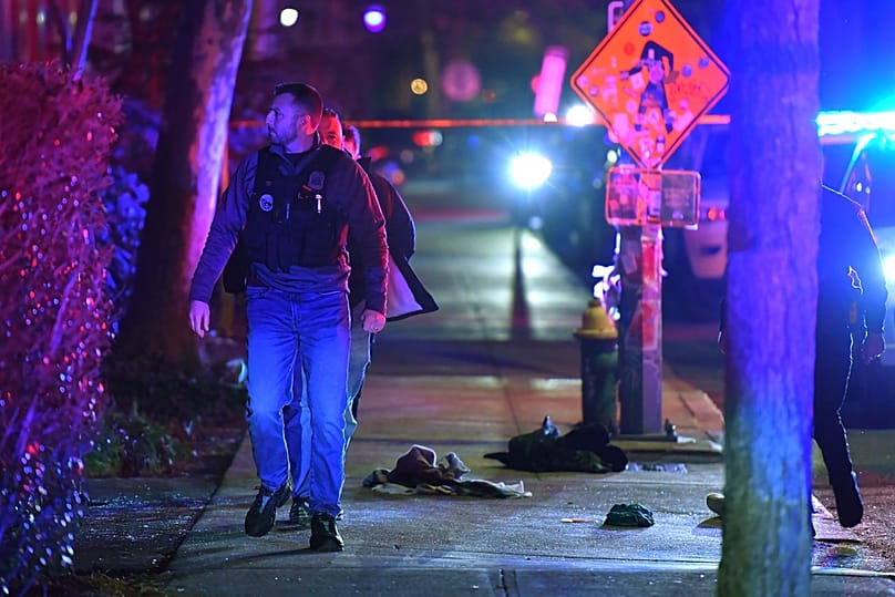 Law enforcement official walks past articles of clothing on a sidewalk near an entrance to Brown University, Saturday, Dec. 13, 2025, in Providence, Rhode Island