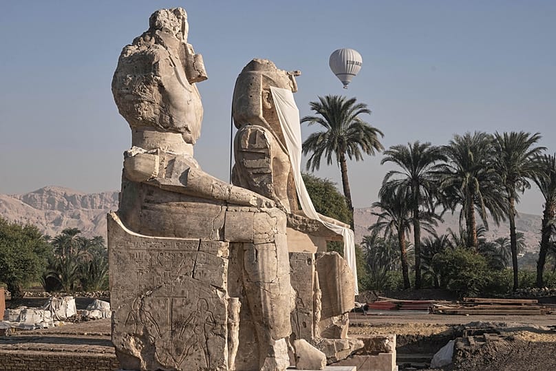 A hot air ballon flys over the assembly of two giant alabaster statues for Pharoah Amenhotep III, before the official opening, in Luxor, Egypt, Dec. 14, 2025