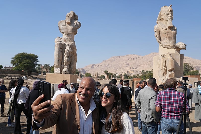 Visitors take photos with the two giant reassembled alabaster statues of Pharoah Amenhotep III, in the southern city of Luxor, Egypt, Sunday, Dec. 14, 2025.