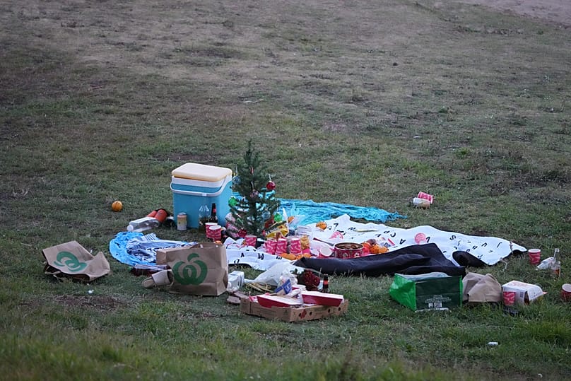 Un petit sapin de Noël trône au centre d'un pique-nique abandonné sur la plage de Bondi après une fusillade signalée à Sydney, le dimanche 14 décembre 2025.