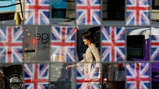 El trayecto al trabajo se refleja en el cristal de la ventana de un pub, decorada con banderas británicas, en Londres. 23 de julio de 2012.