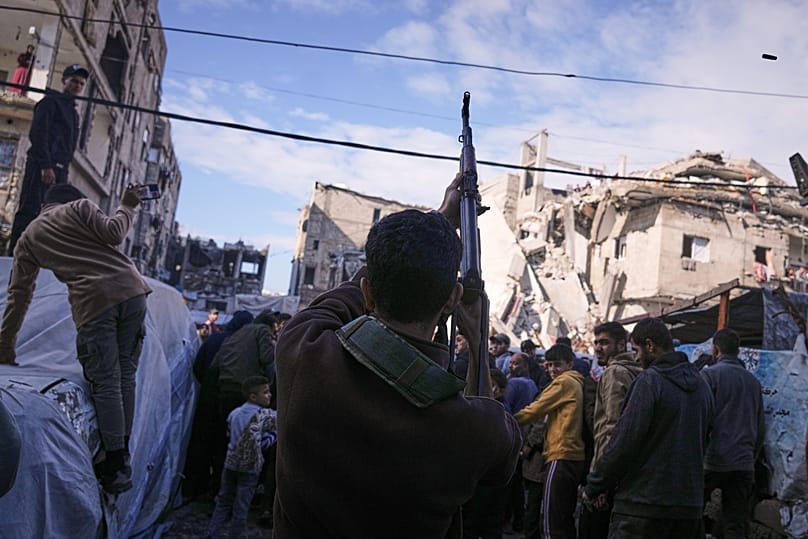 A Palestinian man fires in the air during the funeral of Hamas' Al-Qassam Brigades operatives, killed in an Israeli strike Saturday, in Gaza City, Sunday, Dec. 14, 2025.