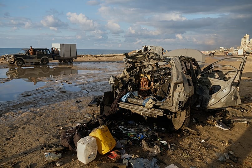 Palestinians drive past a destroyed car following an Israeli strike in Gaza City, Saturday, Dec. 13, 2025.