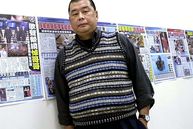 Jimmy Lai, owner of the Hong Kong newspaper Apple Daily, poses next to dry runs of a soon to be launched Taiwanese newspaper taped to his office wall, April 7, 2003, in Taipei